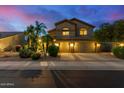 Two-story home featuring a three car garage, desert landscaping and mature palm trees at twilight at 4822 E Charleston Ave, Scottsdale, AZ 85254