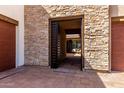 View of the property's stone-framed gated entrance with a tiled walkway leading to a secluded courtyard at 1330 E Monte Way, Phoenix, AZ 85042