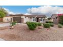 Single-story home featuring a desert landscape, two car garage, and well-maintained shrubs at 16183 W Devonshire Ave, Goodyear, AZ 85395