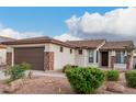 Attractive home with a two-car garage and meticulously designed desert landscape with lush green plants at 16183 W Devonshire Ave, Goodyear, AZ 85395
