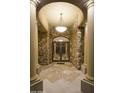 Impressive entryway with stone walls, marble floors, and decorative iron door, lit by a modern chandelier at 16716 S 32Nd Ln, Phoenix, AZ 85045