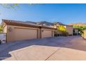 Spacious three-car garage with ample parking space and exterior lighting, set against a mountain backdrop at 16716 S 32Nd Ln, Phoenix, AZ 85045