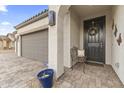 Cozy front porch with a wrought-iron bench, decorative wall art, and welcoming wreath on the dark-colored front door at 1749 W Posada St, Coolidge, AZ 85128