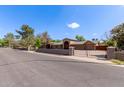 Gated single-story home with brick facade, mature trees, and a neatly maintained landscape at 2043 E Quartz St, Mesa, AZ 85213