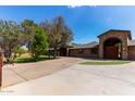 Expansive driveway leads to a single-story brick home with stone accents, arched entryway, and mature landscaping at 2043 E Quartz St, Mesa, AZ 85213