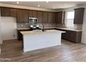 Modern kitchen features an island, stainless steel appliances, dark cabinets, and light countertops at 22359 W Monona Ln, Surprise, AZ 85387