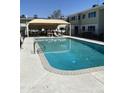 Community pool with shaded seating area surrounded by wrought iron fence at 2569 W Berridge Ln # D-115, Phoenix, AZ 85017