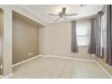 Spacious bedroom featuring tiled floors, neutral paint, a ceiling fan, and a window with curtains at 2947 N Evergreen St, Buckeye, AZ 85396