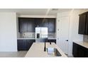 Modern kitchen featuring stainless steel appliances, dark cabinets, light countertops, and stylish tile backsplash at 22392 W Monona Ln, Surprise, AZ 85387
