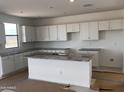 Bright kitchen with granite countertops, white cabinets, and a central island with sink at 22400 W Monona Ln, Surprise, AZ 85387