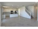 Bright, open living area with staircase and adjacent kitchen featuring modern, white cabinets at 22400 W Monona Ln, Surprise, AZ 85387