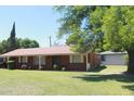 Quaint one-story brick house featuring a lush green lawn, mature trees, and a welcoming front facade at 3942 N 38Th St, Phoenix, AZ 85018