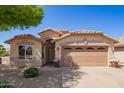 Welcoming single-story home with a two-car garage and tidy desert landscaping under a clear blue sky at 44454 W Oster Dr, Maricopa, AZ 85138