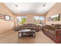Formal living room with plush sofas, carpeted floors, and sunny windows offering neighborhood views at 44454 W Oster Dr, Maricopa, AZ 85138