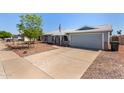 Single-story home with a light blue exterior, two-car garage, and desert landscaping in the front yard at 4915 W Libby St, Glendale, AZ 85308