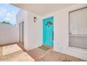 Close-up of a bright turquoise front door, set within a white stucco frame with charming desert landscaping at 511 E Calavar Rd, Phoenix, AZ 85022