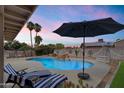 Inviting backyard pool with lounge chairs, shade umbrella, decorative string lights and desert landscaping at 13411 N 50Th St, Scottsdale, AZ 85254
