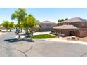 View of the home's side exterior near a basketball court, with grass and trees along the street at 15725 W Yucatan Dr, Surprise, AZ 85379