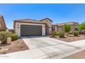 Inviting single-story home with a gray garage door, arched entry, tiled roof, and a low-maintenance landscaped front yard at 19627 W Badgett Ln, Litchfield Park, AZ 85340