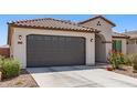 Attractive garage door detail of a single-story home with a tiled roof and desert-style landscaping at 19627 W Badgett Ln, Litchfield Park, AZ 85340