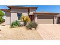 Charming home with desert landscaping in the front yard and a brick paved driveway leading to a two car garage at 44468 W Eddie Way, Maricopa, AZ 85138
