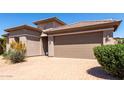 Attractive home exterior showing a brick paved driveway leading to a two car garage and desert landscaping at 44468 W Eddie Way, Maricopa, AZ 85138