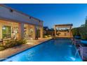 Beautiful backyard pool with a covered patio and built-in grill at twilight at 5512 E Barwick Dr, Cave Creek, AZ 85331