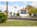 Charming Spanish-style home with a red tile roof and blue trim is accentuated by lush landscaping and mature palm trees at 6 E Piping Rock Rd, Phoenix, AZ 85022