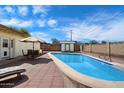 Backyard features a sparkling pool with an umbrella-shaded table and lounging area on a brick patio at 8042 N 28Th Ave, Phoenix, AZ 85051