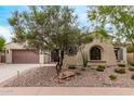 Beautiful home exterior featuring desert landscaping, neutral stucco, and a charming arched window at 12906 W Oyer Ln, Peoria, AZ 85383