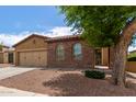 Attractive single-story home with stone accents, a two-car garage, and mature tree in the front yard at 16987 W Hammond St, Goodyear, AZ 85338