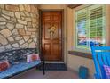 Cozy entryway showcasing a wooden door with a welcome sign, bench, and stone accents at 20423 W Springfield St, Buckeye, AZ 85396