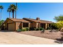 A charming brick home with a two-car garage, desert landscaping, and a long driveway sits on a sunny street at 2114 E Hale St, Mesa, AZ 85213
