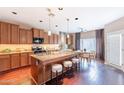 Open kitchen featuring a granite island with seating, wood cabinets, and a dining area at 2323 W Kachina Trl, Phoenix, AZ 85041