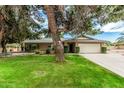 Charming single story home featuring a lush green lawn, mature trees, and a two-car garage at 4317 E Yucca St, Phoenix, AZ 85028
