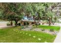 Single story home with a beautifully landscaped front yard with mature trees and a stone pathway at 4317 E Yucca St, Phoenix, AZ 85028