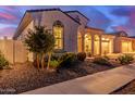 Charming home exterior boasts desert landscaping, an arched window, and a cozy entryway under a dusky sky at 5228 S 106Th Pl, Mesa, AZ 85212