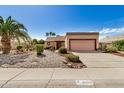 Lovely one-story home with desert landscaping, a palm tree, and a two-car garage is perfect for curb appeal at 6203 W Caribe Ln, Glendale, AZ 85306