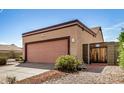 Side view of a two-car garage featuring a pink door, with desert landscaping and a wooden gate at 6203 W Caribe Ln, Glendale, AZ 85306