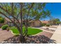 Charming front yard featuring artificial grass, rock landscaping, and a mature shade tree at 7185 W Kimberly Way, Glendale, AZ 85308