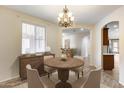 Elegant dining room with wood table, chandelier, cabinet, and lots of natural light from the window at 9165 W Mine Trl, Peoria, AZ 85383