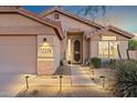 Inviting front entrance with a decorative security door, desert landscaping, and illuminated walkway at 10335 E Morning Star Dr, Scottsdale, AZ 85255