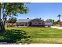 Charming single-story home featuring a well-maintained lawn, mature trees, and a detached garage with a basketball hoop at 1551 E Longhorn Dr, Chandler, AZ 85286