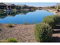 Calm community pond reflecting the sky with surrounding landscaping at 21093 N Willow Rd, Maricopa, AZ 85138