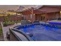Inviting backyard featuring a hot tub with illuminated blue lighting and a shaded pergola at 22977 E Desert Spoon Dr, Queen Creek, AZ 85142