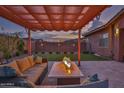 Relaxing backyard patio with a cozy fire pit and comfortable seating beneath a shaded pergola at 22977 E Desert Spoon Dr, Queen Creek, AZ 85142