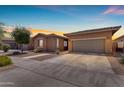 Charming single-story home with a well-maintained lawn and two-car garage at sunset at 22977 E Desert Spoon Dr, Queen Creek, AZ 85142
