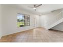 Open-concept living room with a large window, staircase, and a neutral color scheme with tiled floors at 3930 W Monterey St # 136, Chandler, AZ 85226
