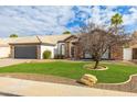 Charming one-story home featuring a lush lawn, mature landscaping, and stone facade accents at 4214 E Morrow Dr, Phoenix, AZ 85050