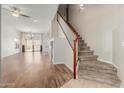 Bright, open-concept living space featuring hardwood floors, neutral walls, and a staircase with carpeted steps and a wooden banister at 7204 S Golfside Ln, Phoenix, AZ 85042